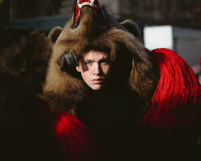 Person in a bear costume surrounded by red fabric, reminiscent of Renaissance paintings.