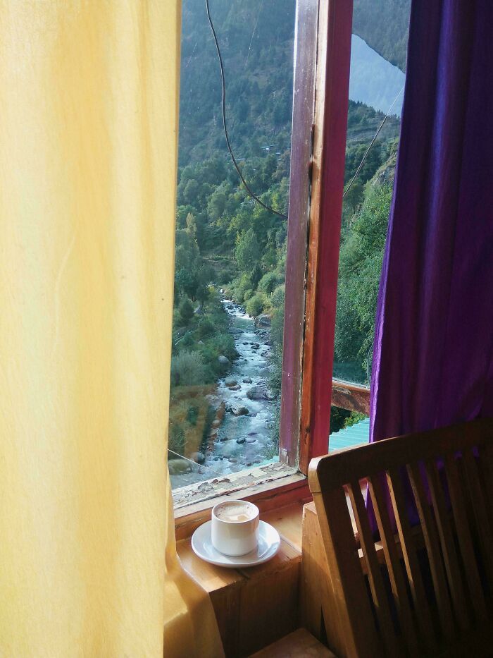 Cozy scene with a coffee cup on the window sill, resembling a Renaissance painting, overlooking a scenic river landscape.