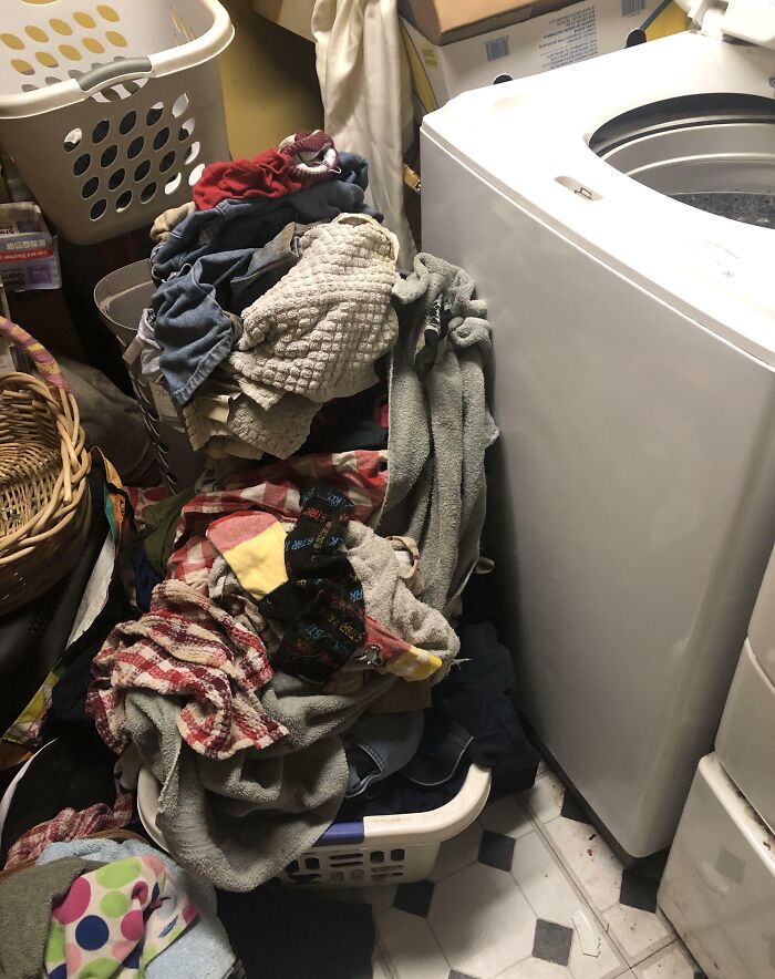 Overflowing laundry basket in a cluttered room, showcasing infuriating boyfriends' and husbands' household habits.