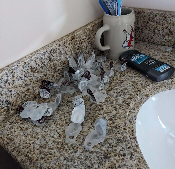 Empty coffee creamers scattered on a bathroom countertop next to a mug and deodorant, illustrating boyfriends' habits.