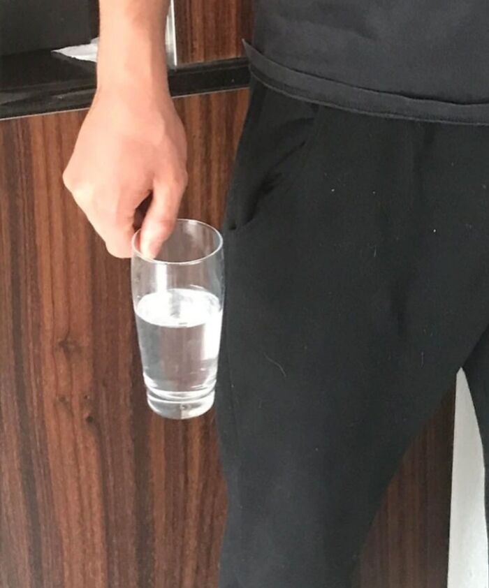 Man holding a glass of water near his pocket, showcasing boyfriends' infuriating actions.