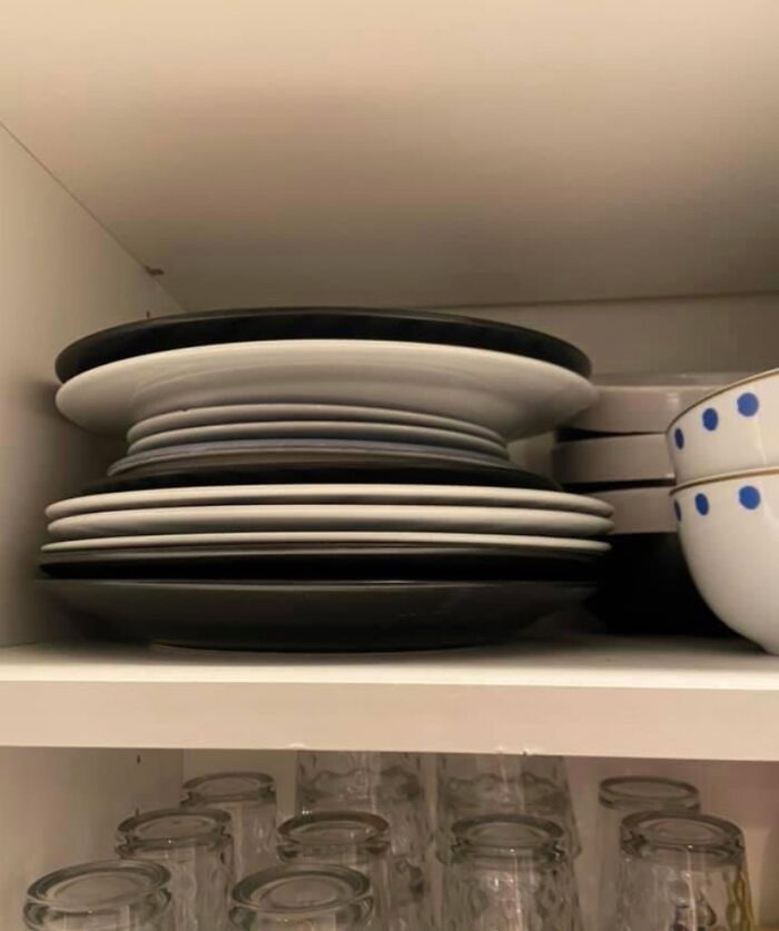 Stacked plates in a kitchen cabinet, illustrating infuriating boyfriend's organization habits.