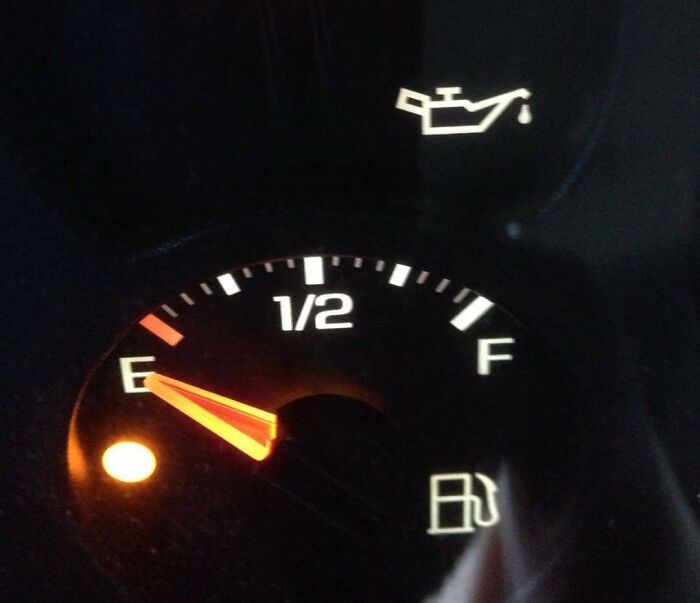 Car dashboard with empty fuel gauge, oil warning light, and infuriating situation for boyfriends and husbands.