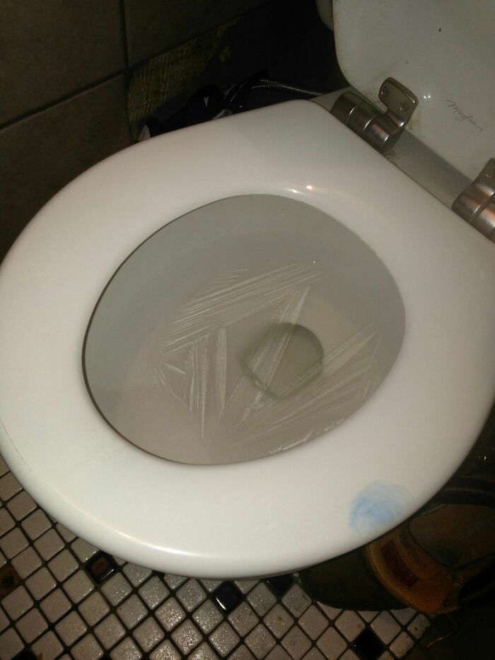 White toilet with plastic wrap cover, creating a humorous trap.