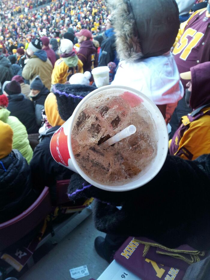 Frozen drink in a cup held in a cold winter setting with a crowd in warm clothing around.