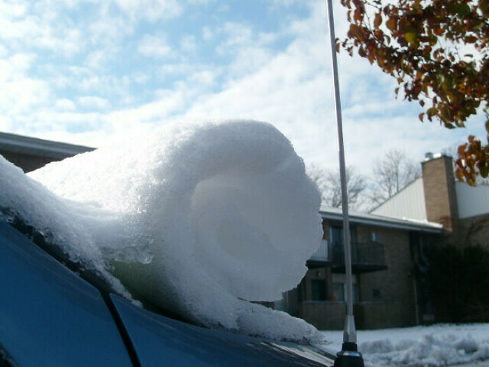 Close-up of ice rolled on a car roof under a cloudy sky, capturing a unique winter scene.