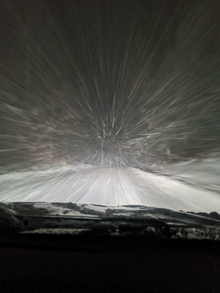 Snowstorm at night viewed from a car windshield, capturing an intense ice-cold winter scene.