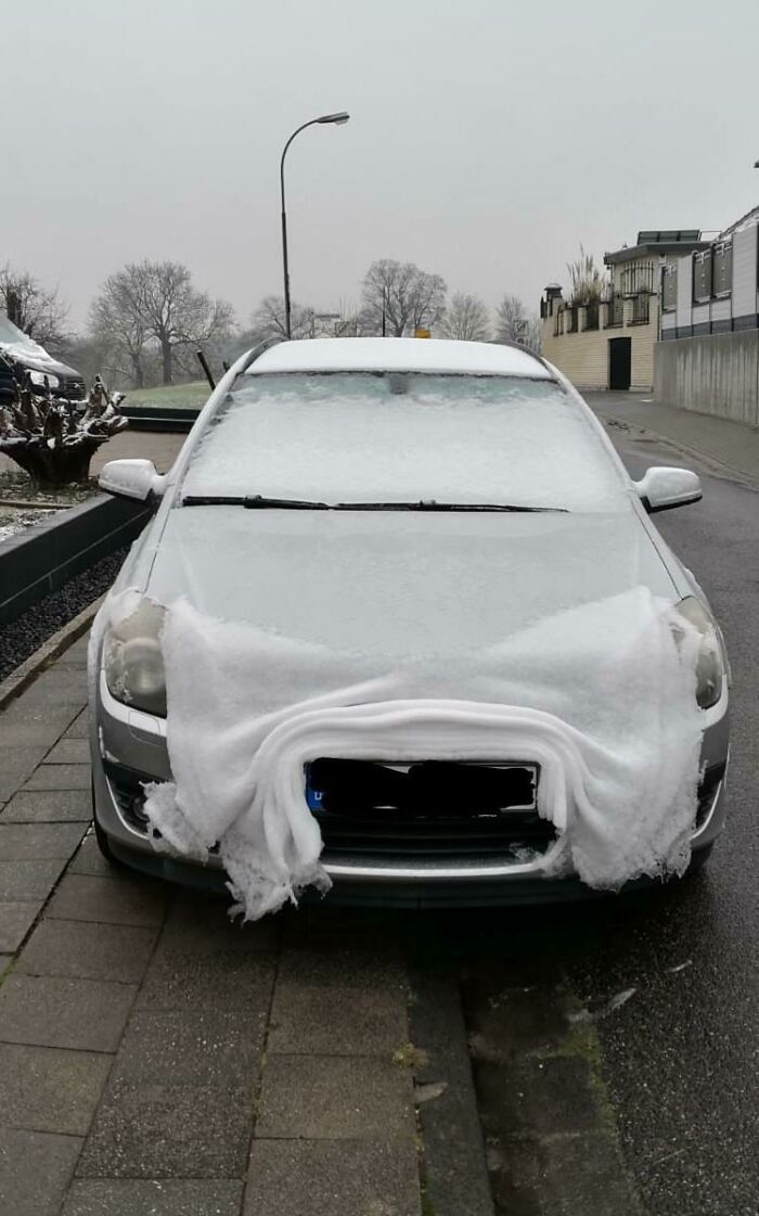 Car covered in snow and ice on a cold winter day, with snow forming an interesting shape on the bumper.