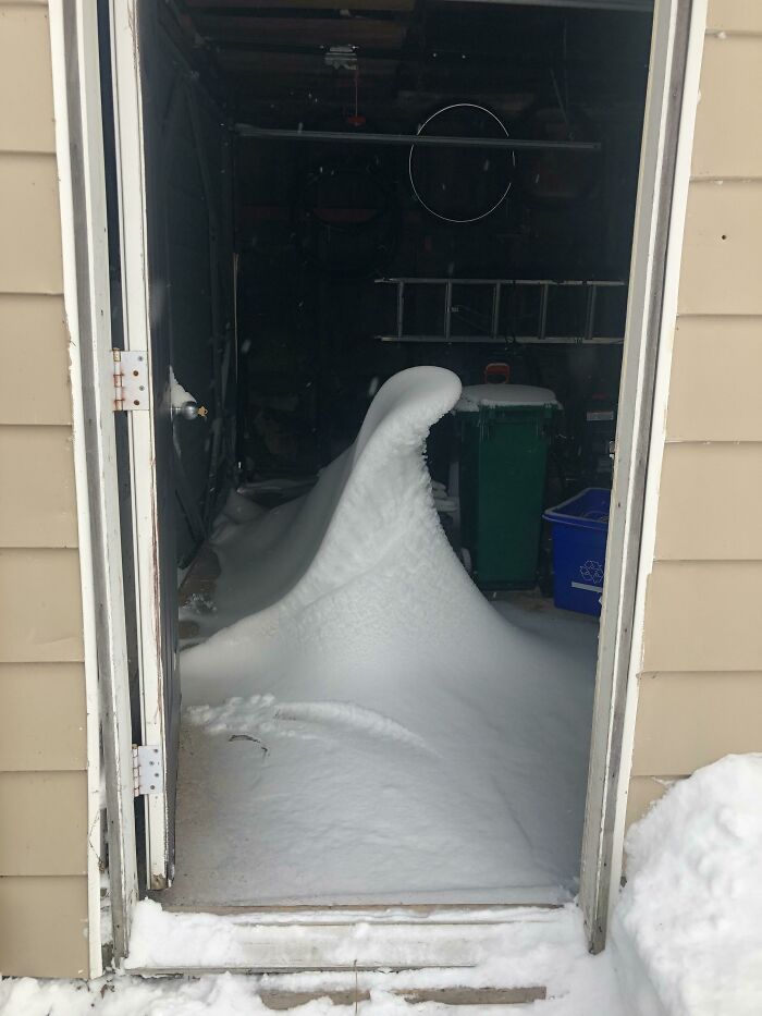 Snow drift entering a garage, showcasing ice-cold winter conditions.