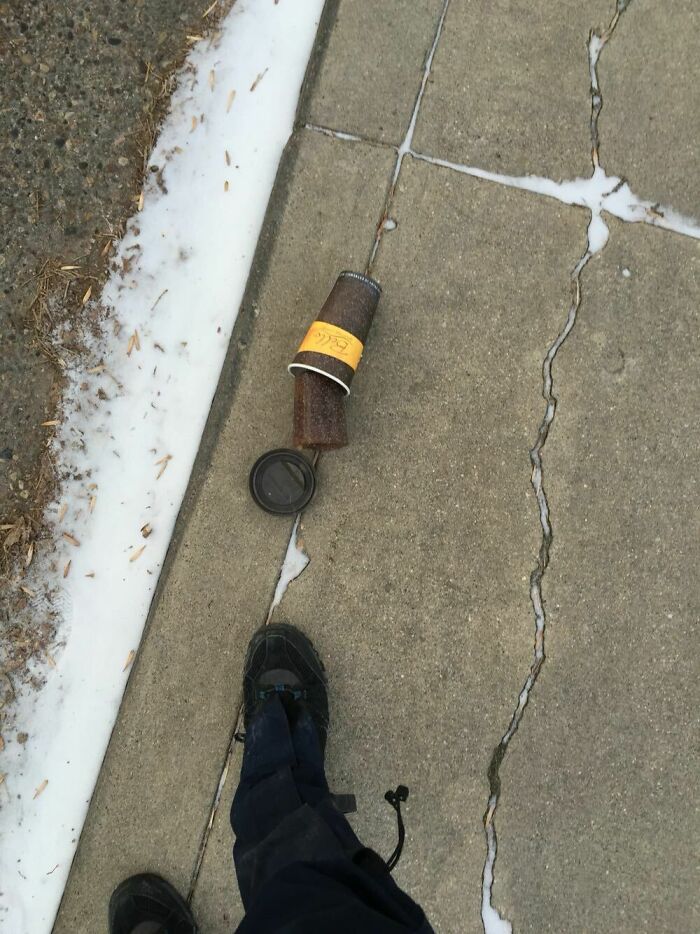 Frozen coffee cup on a snowy sidewalk, illustrating an ice-cold winter scene.