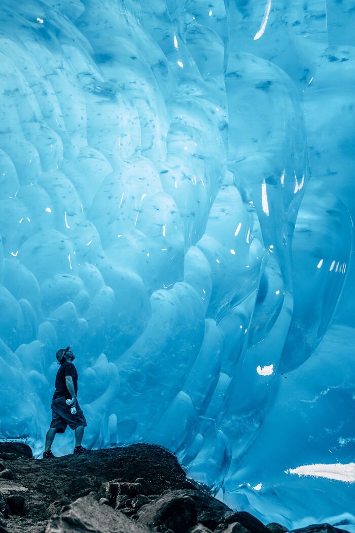 Person in a cap gazing at massive ice formations, embodying the essence of ice-cold winter scenes.