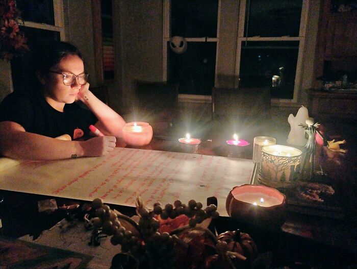 A person studying by candlelight, resembling a Renaissance painting scene, with candles illuminating the table.