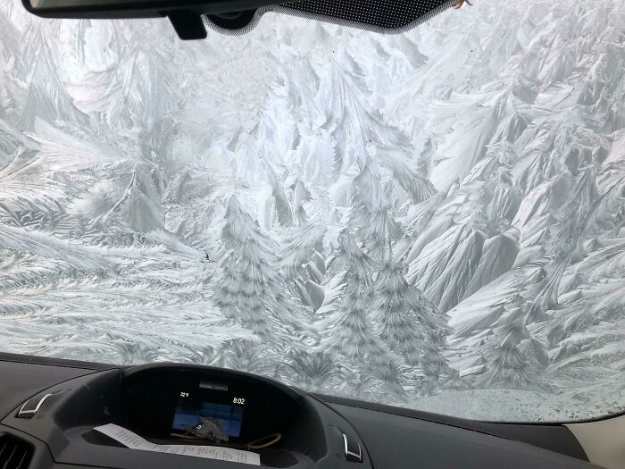 Frost patterns on a car windshield, showcasing ice-cold winter scenery.