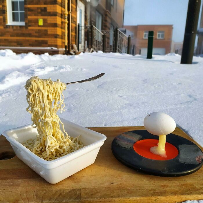 Frozen noodles and egg in a snowy setting, showcasing ice-cold winter weather.