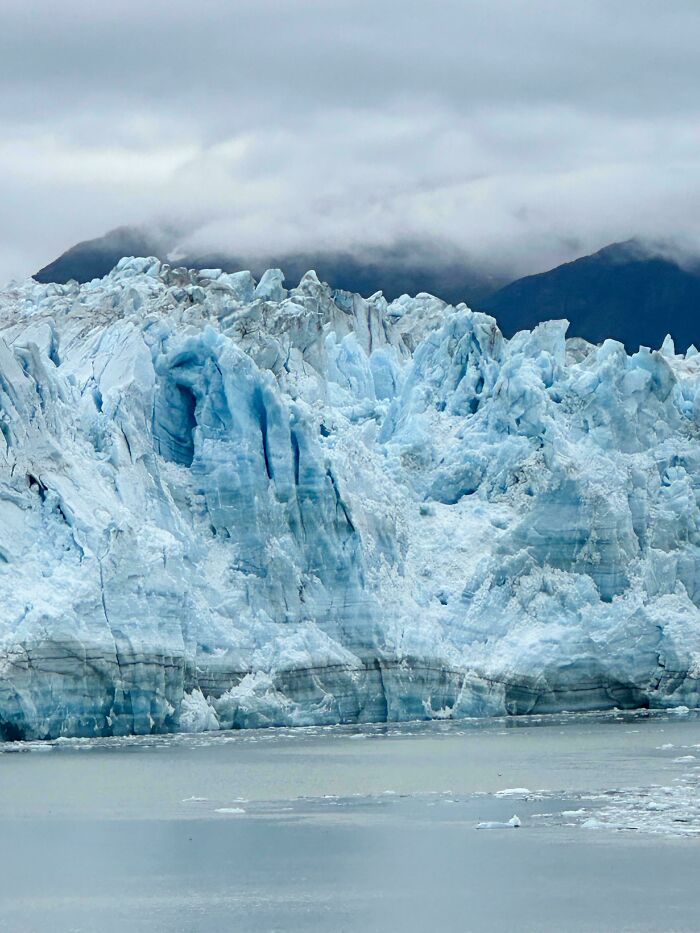 Majestic ice-cold glacier against a backdrop of misty mountains and cloudy sky.