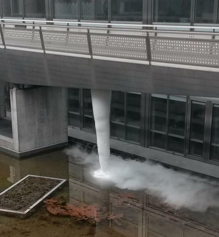 Frozen waterfall under a bridge, showcasing ice-cold winter scene in an urban environment.