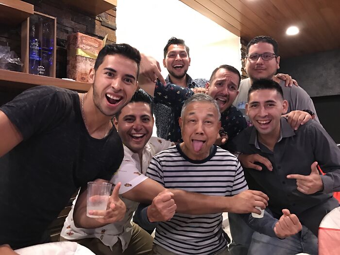 A group of men, including a playful in-law in a striped shirt, posing joyfully at a party.