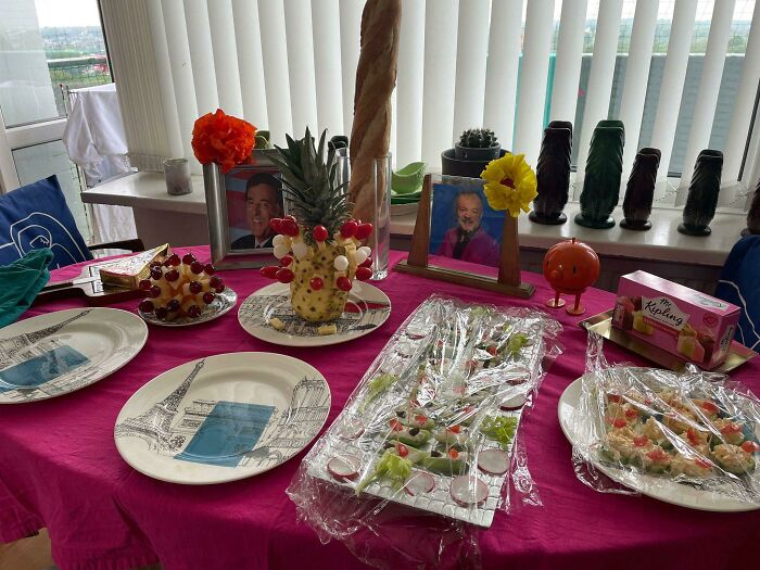 A humorous in-law-themed table with creative fruit displays and family photos.