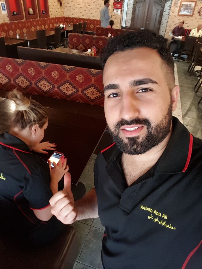 A waiter at a kebab restaurant, smiling and giving a thumbs-up, illustrating the concept of good-funny-bosses.