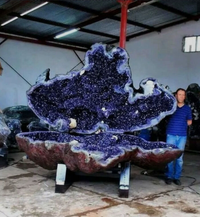 Giant geode displayed in a warehouse, showcasing an absolute unit of amethyst crystals.