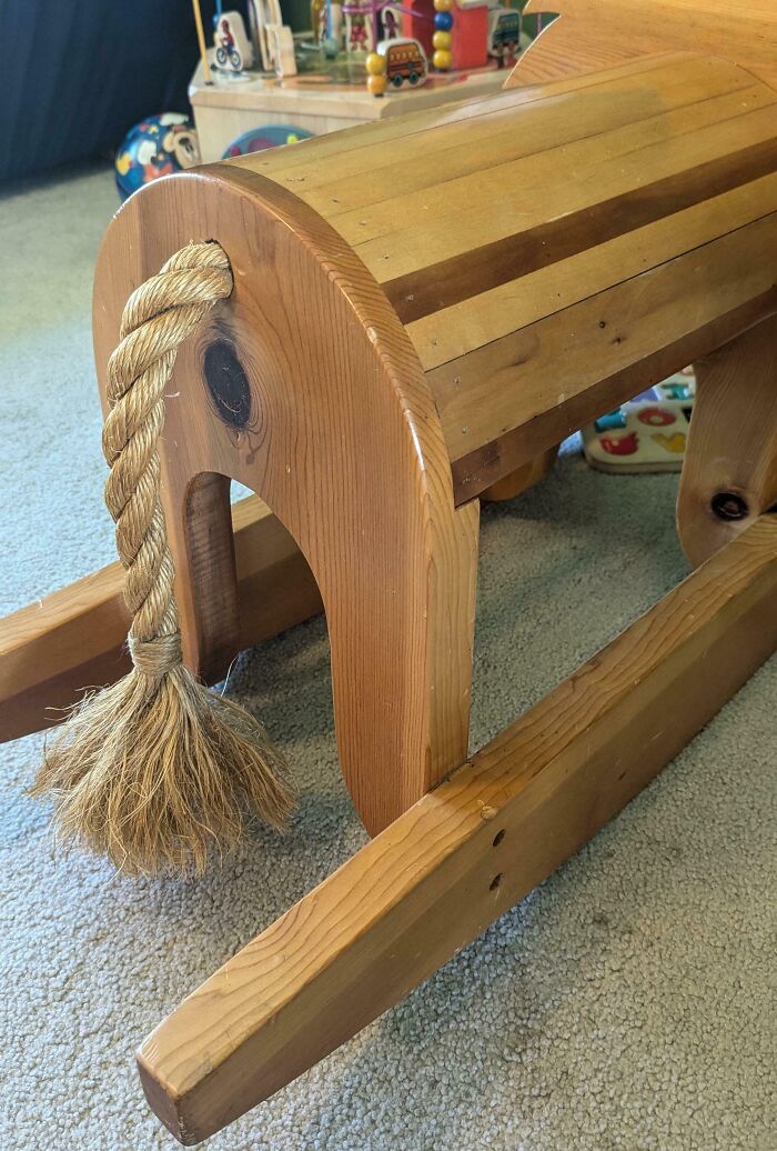 Wooden rocking horse in living room, comical design with rope tail, linked to Hilarious-In-Laws theme.