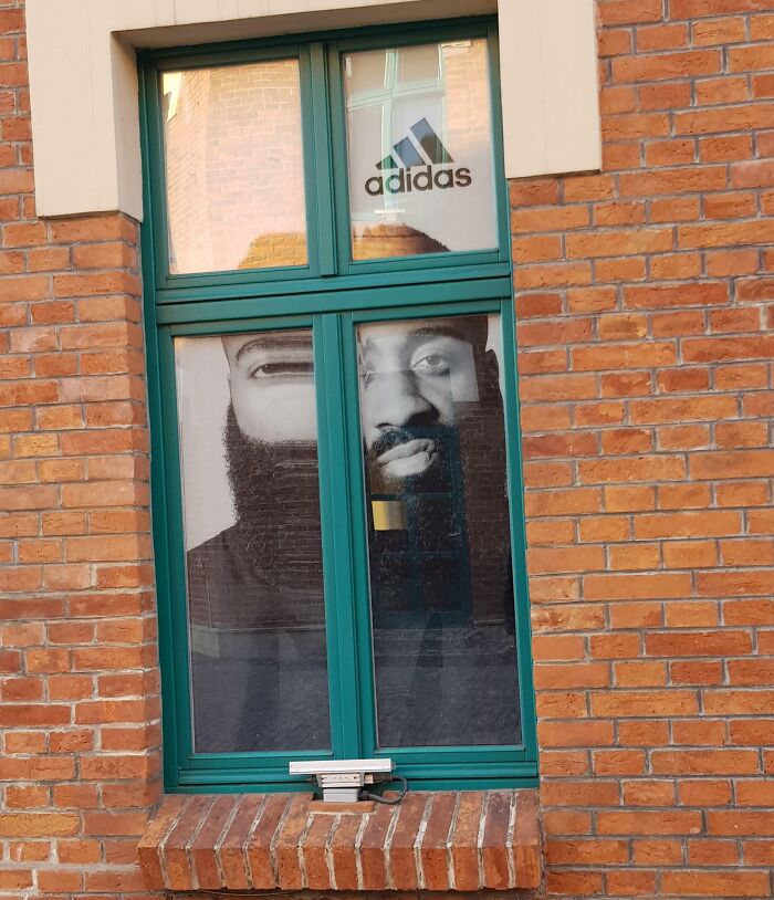 Adidas ad fail with a poster misaligned behind a window, creating a humorous image.