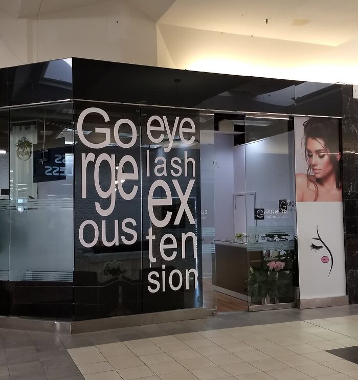 Storefront with humorous signage fail, showing staggered words for "Gorgeous eyelash extension" in bold letters.