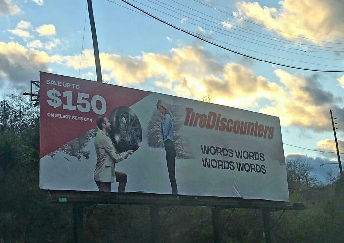 Funny ad fail with a billboard showing a man holding a tire, and text replaced by "WORDS WORDS WORDS."