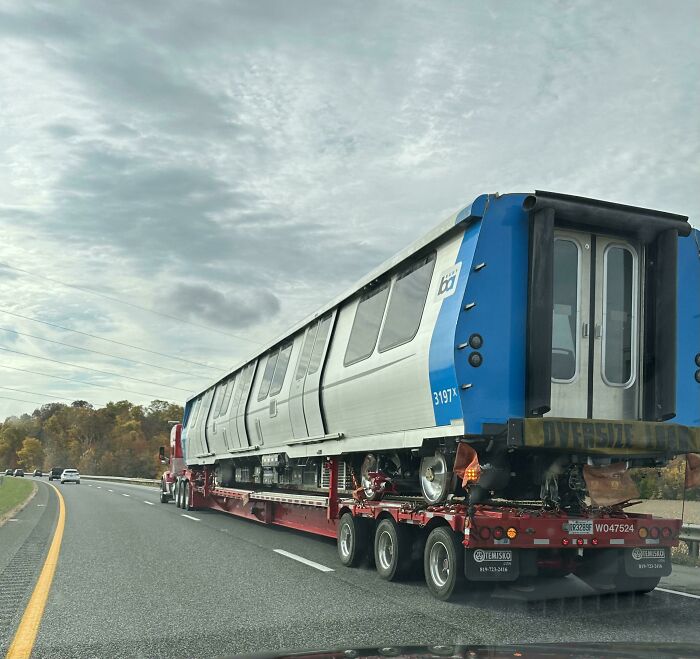 Train car being transported on a truck on the highway, showcasing interesting things on the road.