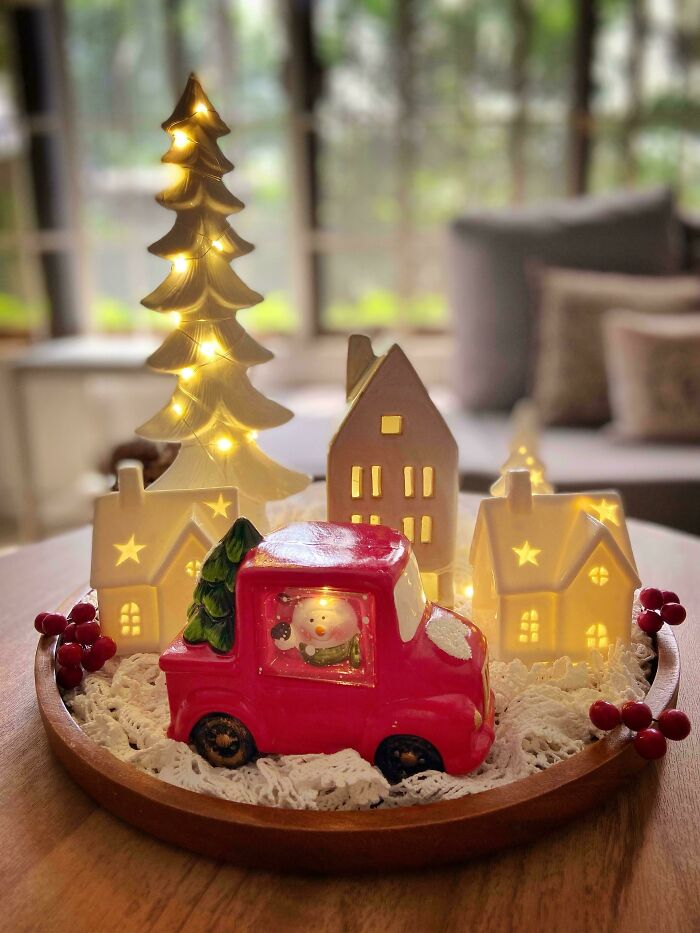 Festive Christmas decorating idea with a red truck, ceramic houses, and a lit Christmas tree centerpiece.