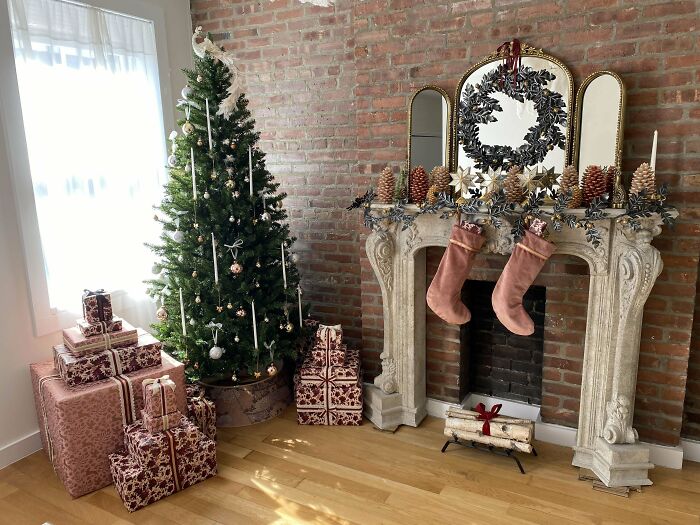 Christmas-decorating-ideas with a tree, wrapped gifts, and stockings over a mantle in a cozy living room.