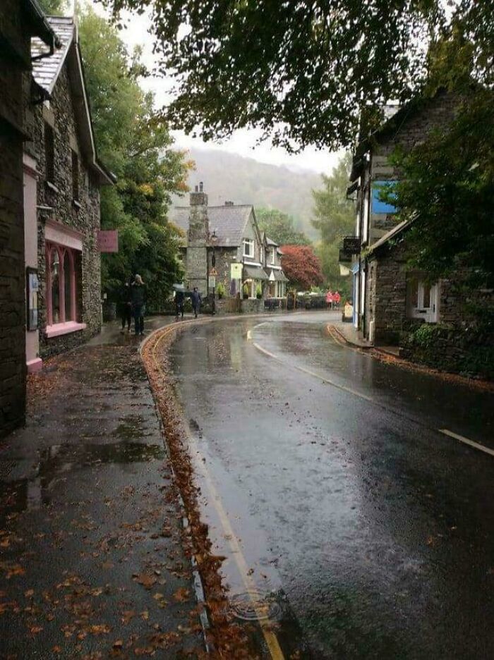 Charming British village street in autumn, with wet pavement and stone houses, capturing delightful UK essence.