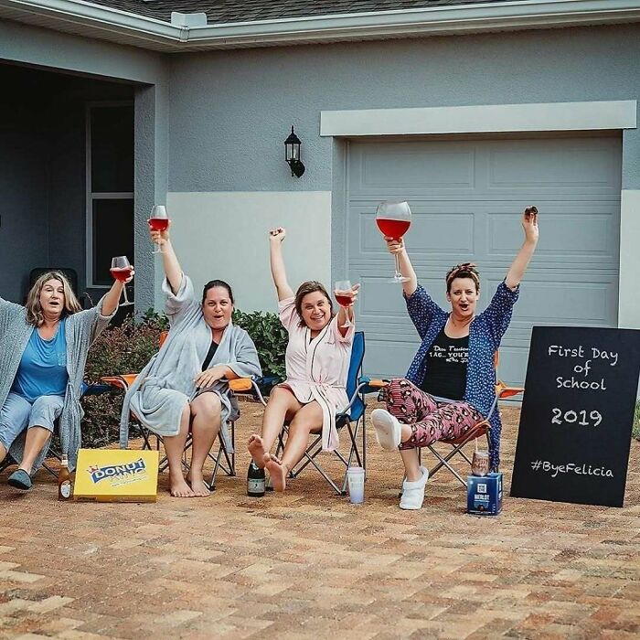 Women-In-Real-Life-Pics: Four women celebrating with drinks, seated in lawn chairs in front of a garage, holding wine glasses.