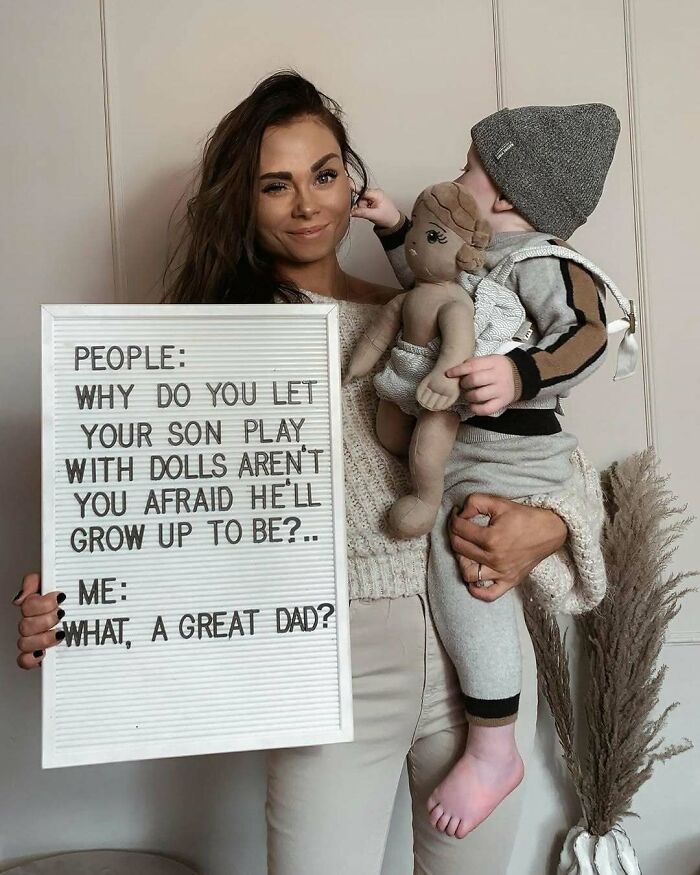 Woman holding a baby and sign about parenting, promoting positive messages in real life.