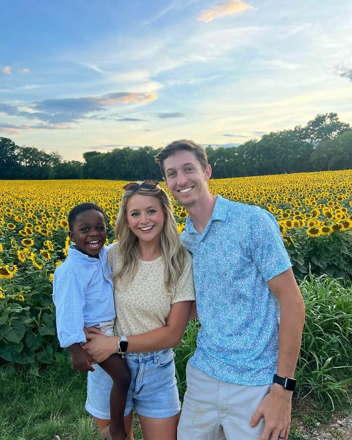 Happy family in a sunflower field, showcasing a heartwarming adoption moment with big smiles under a beautiful sky.