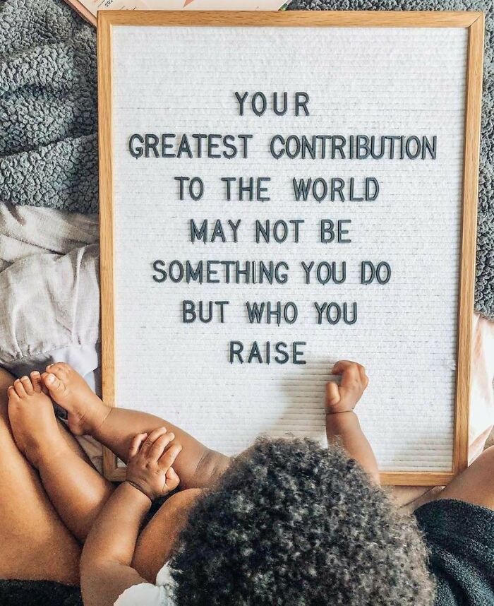 Women with baby reading a motivational quote on a letter board about making contributions through parenting.