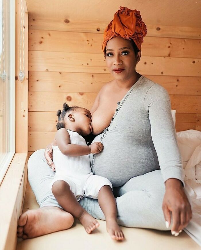 Woman breastfeeding her child in a cozy wooden room, showcasing real-life moments of motherhood.