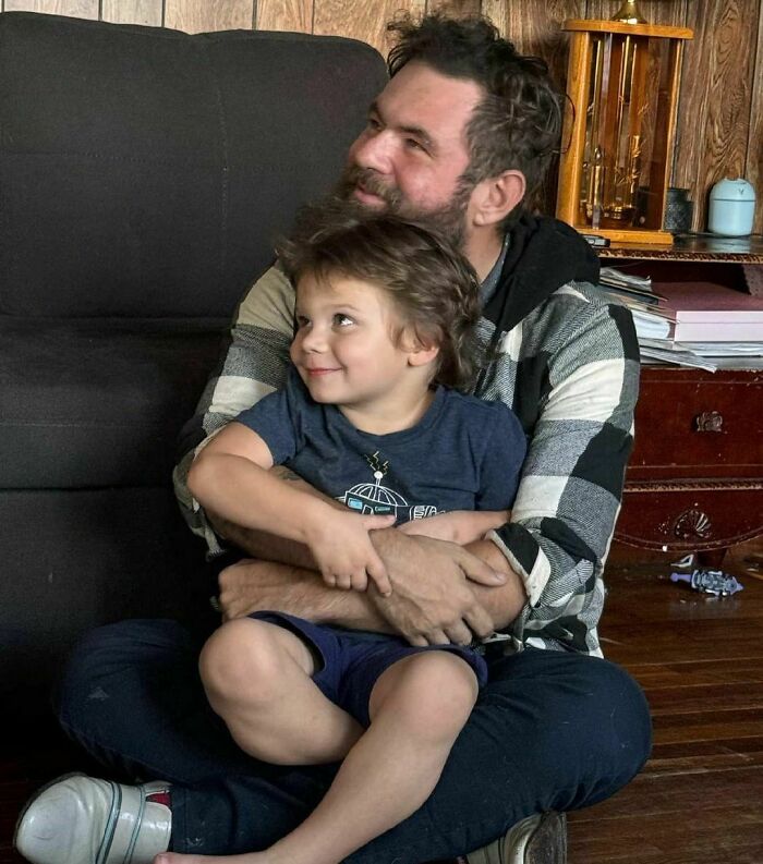 Father and adopted son smiling while sitting on the floor, showcasing a wholesome adoption moment.