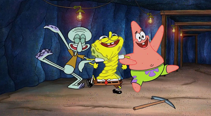 A famous trio from an animated series featuring SpongeBob, Patrick, and Squidward dancing joyfully together in a cave setting with hanging lights.