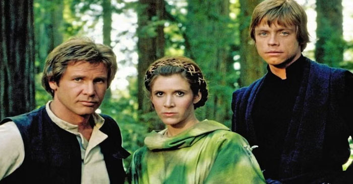 A famous trio from Star Wars, featuring Han Solo, Princess Leia, and Luke Skywalker standing together in a forest setting.