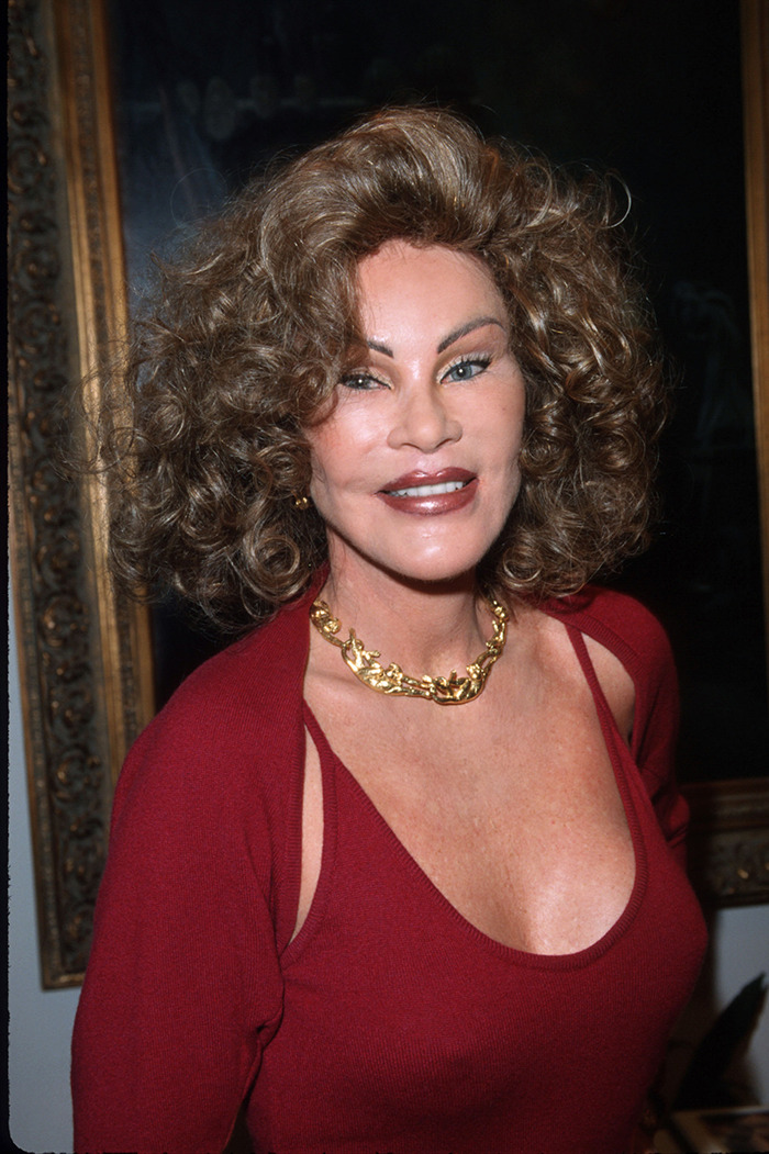 Jocelyn Wildenstein in red top and gold necklace, smiling confidently.