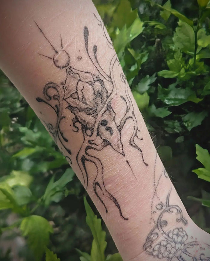 A semicolon tattoo integrated into an intricate design with a blooming rose and abstract lines on the forearm, symbolizing growth and resilience.