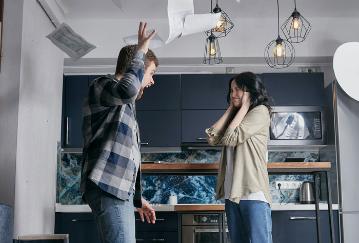 Man and woman arguing in a kitchen; college fund disagreement for son's future sparks tension.