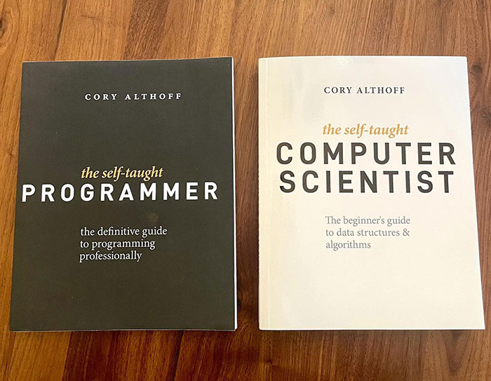 Two books titled "The Self-Taught Programmer" and "The Self-Taught Computer Scientist" by Cory Althoff, Bobbi Althoff’s Husband placed on a wooden surface.