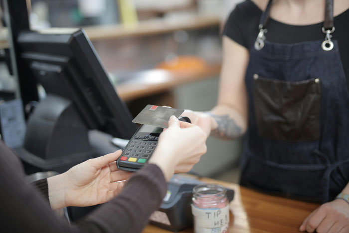 Customer paying with card at a café counter, depicting an added fee situation.