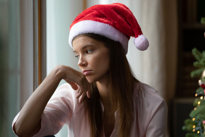 Woman in Santa hat looking thoughtful, avoiding unwanted holiday gifts.