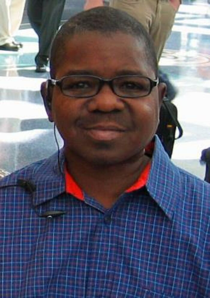 Man wearing glasses and a blue checkered shirt at a public event, embodying experiences of meeting celebrities.