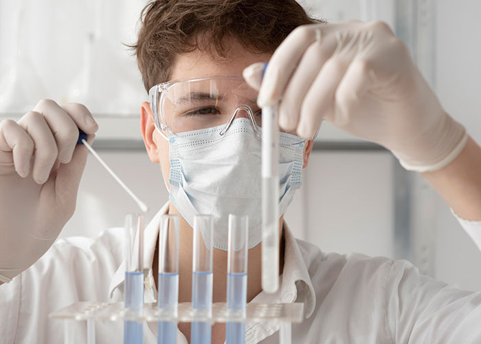 Scientist in a lab coat and goggles examining test tubes, exemplifying a gut feeling in action.