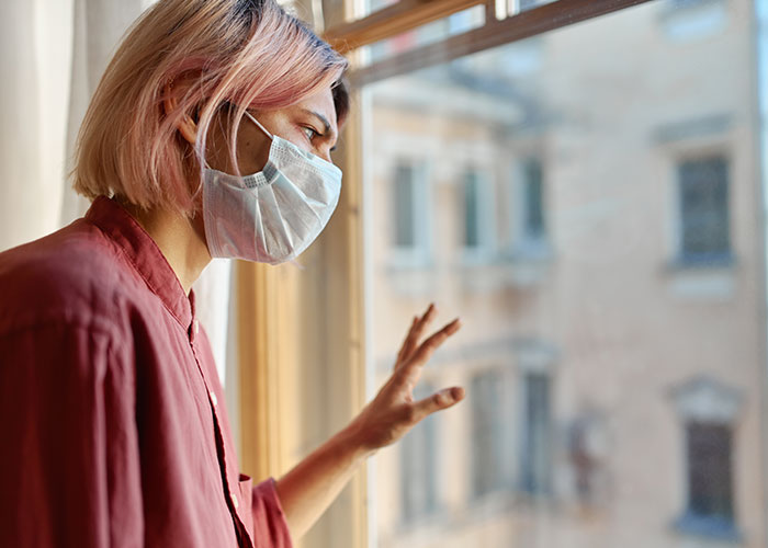 Person with face mask looking out the window, representing intuition and gut feelings.