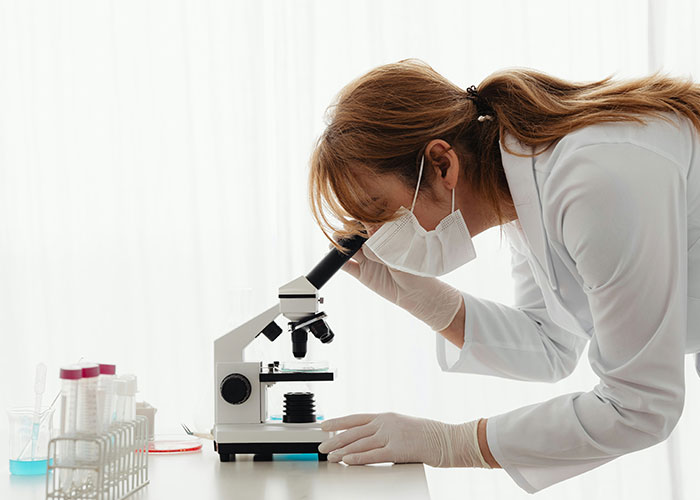 Scientist with gut feelings examines samples under a microscope.